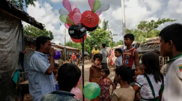 Um homem vende balões para crianças rohingya em um campo de refugiados, em Cox's Bazar, Bangladesh, em 27 de setembro de 2024 [Stringer/Reuters]