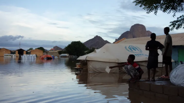 Crianças deslocadas perto de uma tenda do ACNUR inundada após fortes chuvas em Kassala, Sudão [Arquivo: Mohamed Abdulmajid/Reuters]