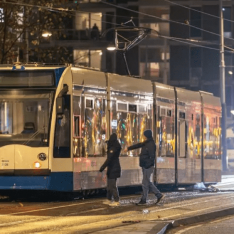 Pedestres se aproximam de um bonde danificado no distrito de Niew-West, em Amsterdã, depois que um grupo incendiou o veículo com fogos de artifício, em 11 de novembro de 2024. AFP - TALHA ANDAC