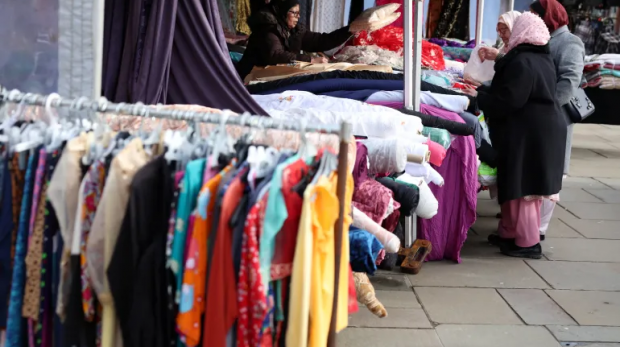 Mulheres em Rochdale compram material em uma barraca de mercado antes da eleição parlamentar suplementar em 19 de fevereiro de 2024 [Arquivo: Phil Noble/Reuters]