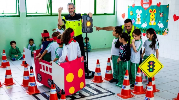 Minicircuito de trânsito com carros de papelão e sinalização realista ajuda crianças a compreenderem a importância do respeito às regras viárias. Imagem: Eduardo Soares