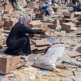 Uma mulher se agacha ao lado de caixas da Fundação Humanitária de Gaza, apoiada pelos EUA, enquanto os palestinos se reúnem para coletar o que resta de suprimentos de emergência do centro de distribuição da Fundação Humanitária de Gaza, em Rafah, no sul da Faixa de Gaza, em 5 de junho de 2025.
(crédito da foto: STRINGER / REUTERS)
