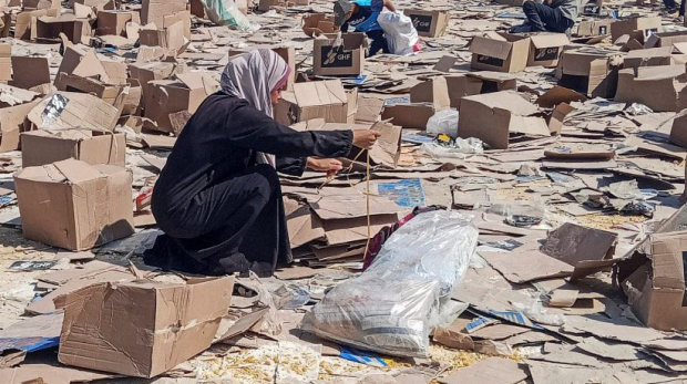 Uma mulher se agacha ao lado de caixas da Fundação Humanitária de Gaza, apoiada pelos EUA, enquanto os palestinos se reúnem para coletar o que resta de suprimentos de emergência do centro de distribuição da Fundação Humanitária de Gaza, em Rafah, no sul da Faixa de Gaza, em 5 de junho de 2025.
(crédito da foto: STRINGER / REUTERS)