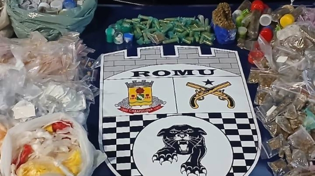 Capô da viatura da ROMU exibe centenas de porções de drogas apreendidas, incluindo cocaína, maconha, crack e lança-perfume. A operação ocorreu em pontos estratégicos da cidade nos dias 4 e 5 de agosto. Ao centro, brasões da GCM e ROMU destacam a ação da corporação. Foto: Prefeitura De Carapicuíba (Redes Sociais/Reprodução)