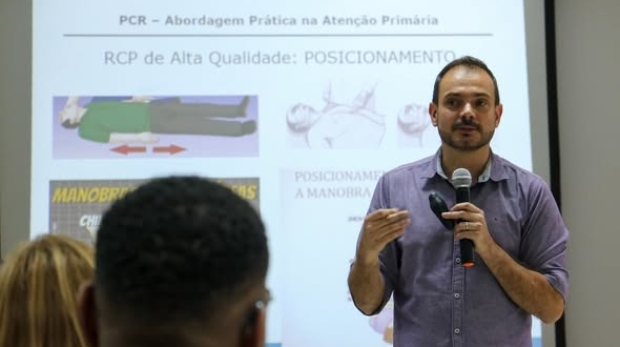 #ParaQueTodosPossamVer Na imagem, um homem segura um microfone e ministra uma palestra sobre RCP diante de uma tela com slides explicativos, enquanto participantes assistem atentos no auditório da Faculdade Estácio de Carapicuíba. Foto: Prefeitura De Carapicuíbs (Redes Sociais/Reprodução)