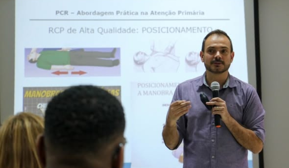 #ParaQueTodosPossamVer Na imagem, um homem segura um microfone e ministra uma palestra sobre RCP diante de uma tela com slides explicativos, enquanto participantes assistem atentos no auditório da Faculdade Estácio de Carapicuíba. Foto: Prefeitura De Carapicuíbs (Redes Sociais/Reprodução)