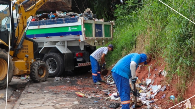 #PraQueTodosPossamVer: Dois trabalhadores recolhem lixo acumulado à beira da estrada, ao lado de um caminhão e uma retroescavadeira. Foto: Prefeitura De Carapicuíba (Redes Sociais/Reprodução)